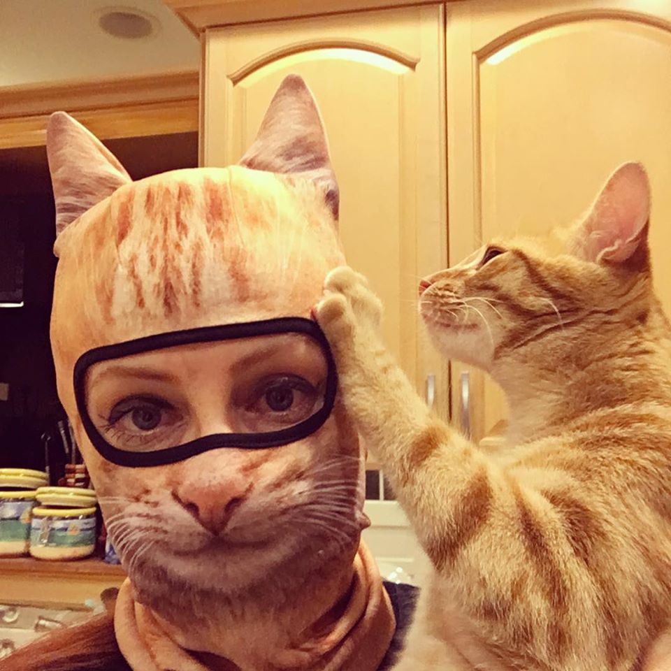 cat looks at woman wearing cat mask
