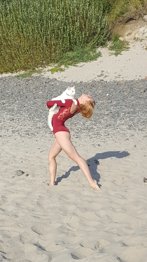 Dancer holds cat on beach