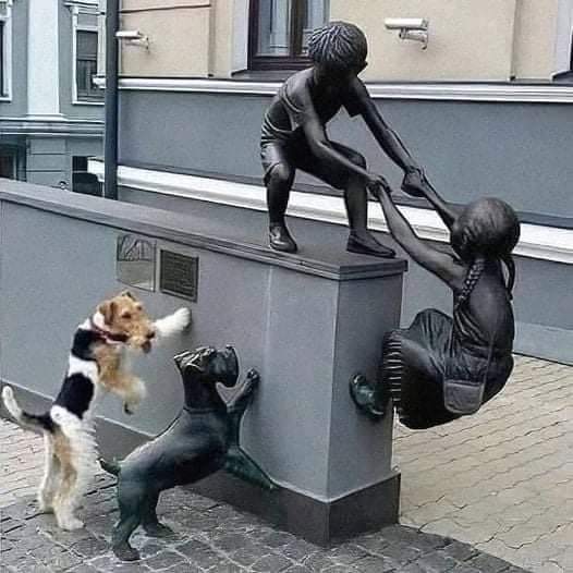 Dog looks at statues depicting dog boy and girl