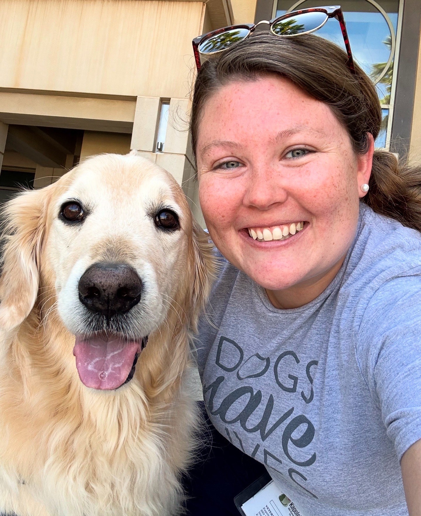 A golden retriever dog poses with a smiling woman