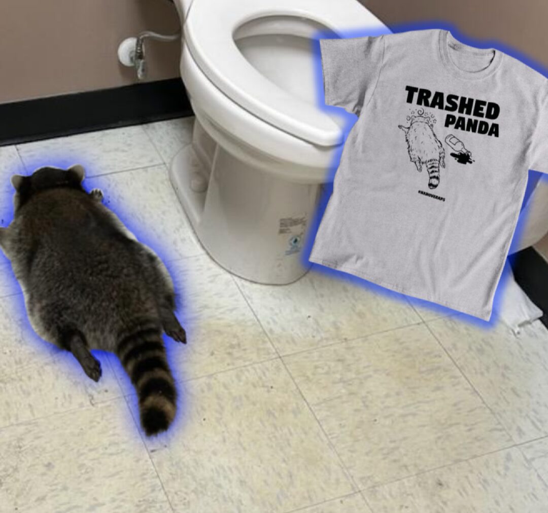 Photograph of a raccoon lying face down in a bathroom next to the toilet. Superimposed on the image is a photo of a t-shirt with a drawing of the raccoon and the words "trashed panda"