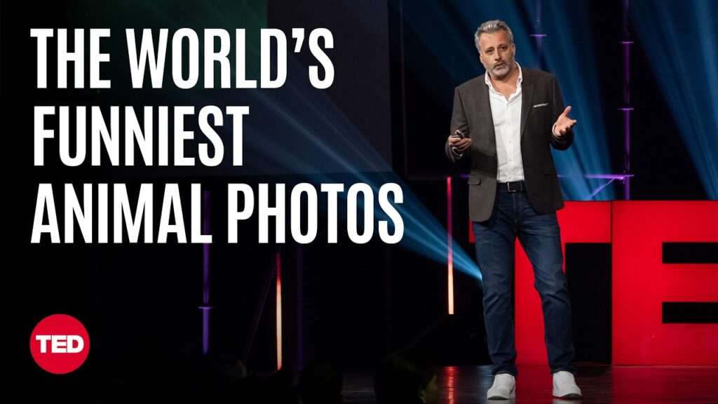 A man stands on a stage speaking to an audience. On the left side of the screen are the words "the world's funniest animal photos"