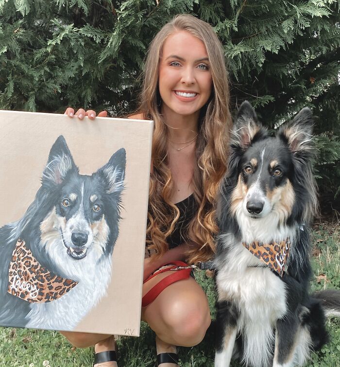 A smiling woman holds a portrait of a dog to her right. The subject of the portrait sits to her left.