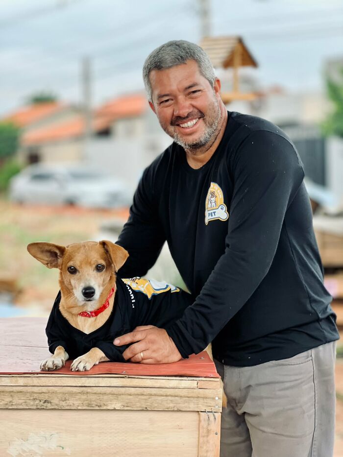A happy man poses next to a dog.